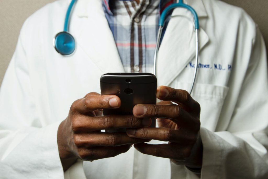 Médico segurando um celular nas mãos